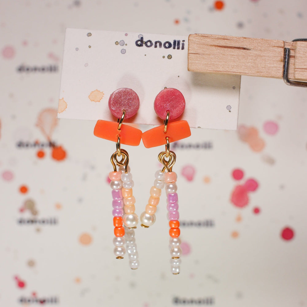 Colorful earrings on a 'donoll' branded card against a patterned background