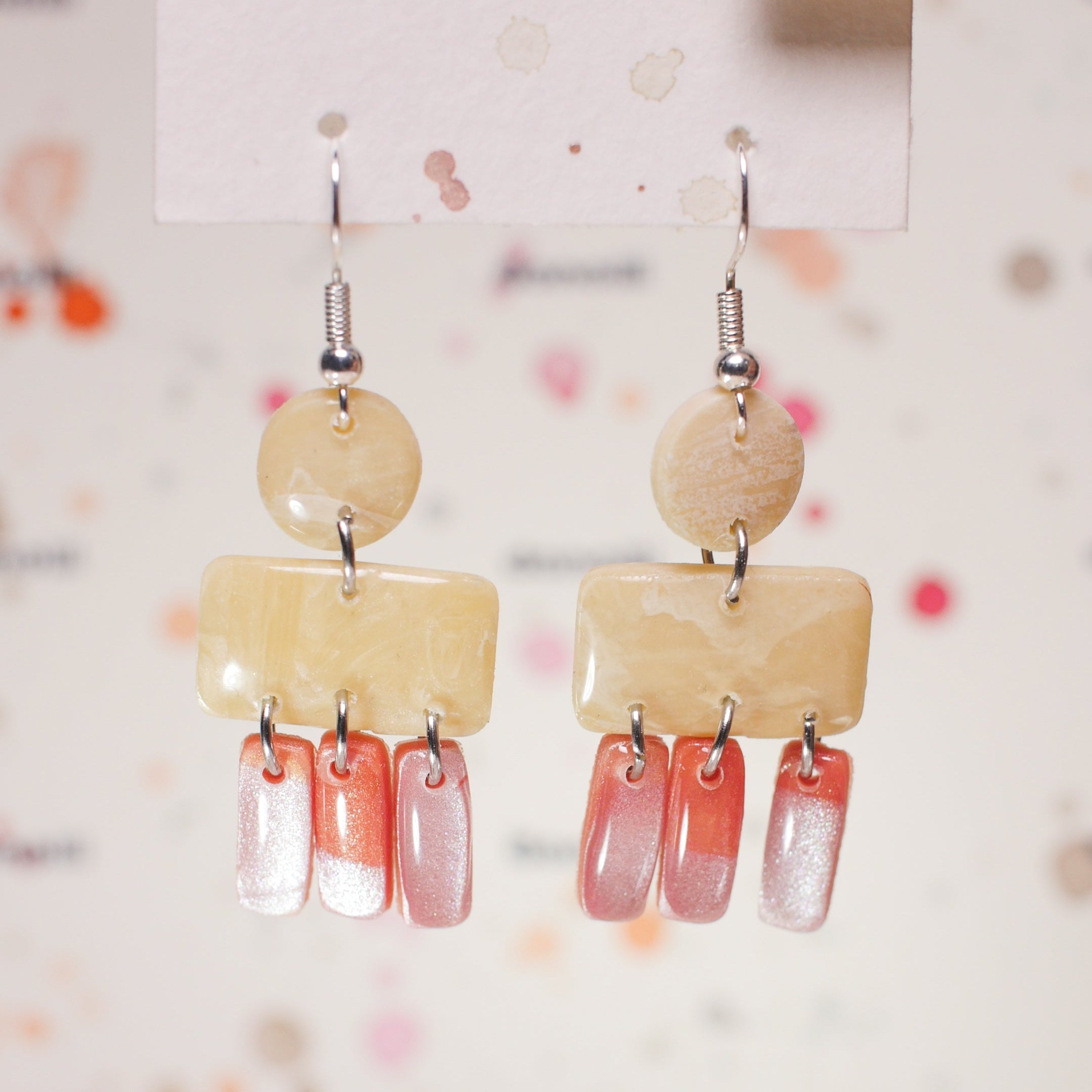 Pair of earrings with beige and pink beads on a white background
